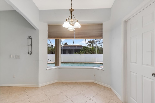 tiled empty room featuring an inviting chandelier