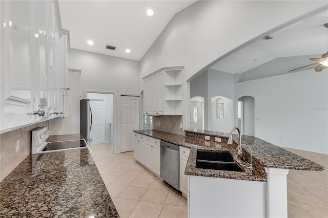 kitchen with dark stone countertops, sink, stainless steel appliances, high vaulted ceiling, and white cabinets