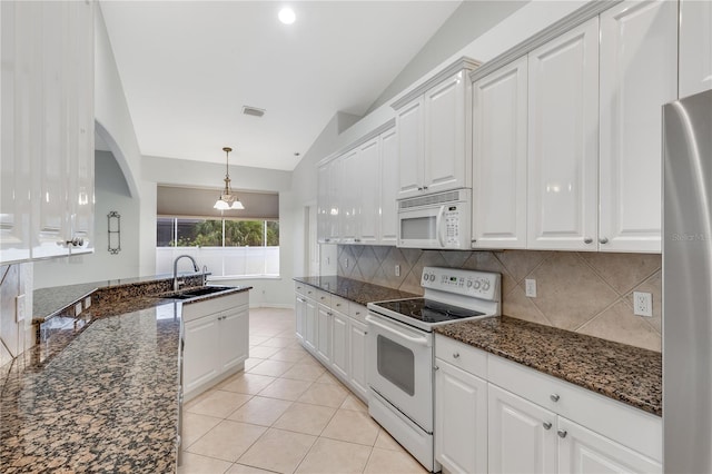 kitchen with white appliances, white cabinets, dark stone countertops, sink, and vaulted ceiling