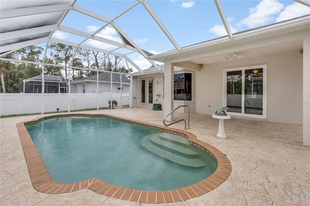 view of pool with glass enclosure, a patio area, and ceiling fan