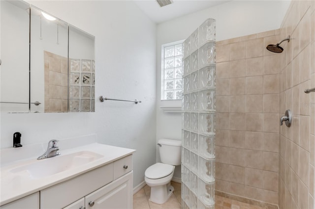 bathroom with tiled shower, vanity, toilet, and tile patterned flooring