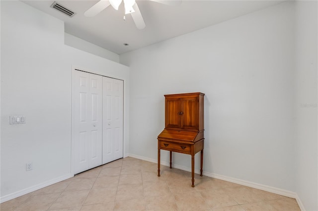 tiled bedroom with ceiling fan and a closet