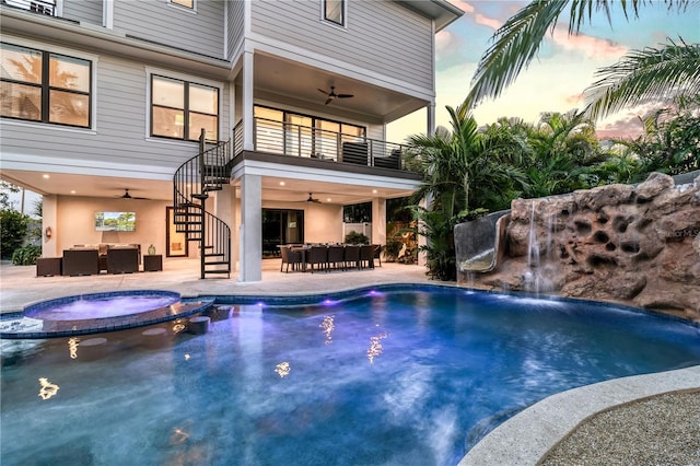 pool at dusk featuring ceiling fan, an outdoor living space, pool water feature, an in ground hot tub, and a patio