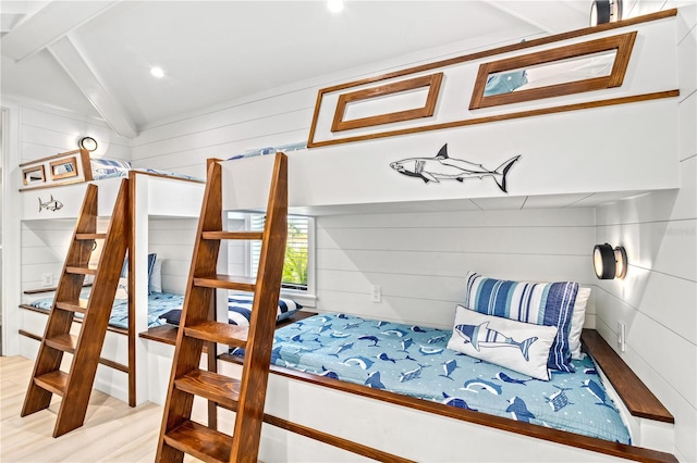 bedroom with light wood-type flooring, vaulted ceiling with beams, and wooden walls