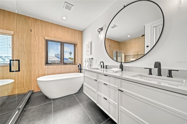 bathroom with tile patterned floors, vanity, a tub to relax in, and wooden walls