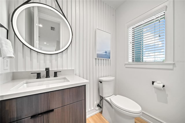 bathroom with hardwood / wood-style floors, vanity, and toilet