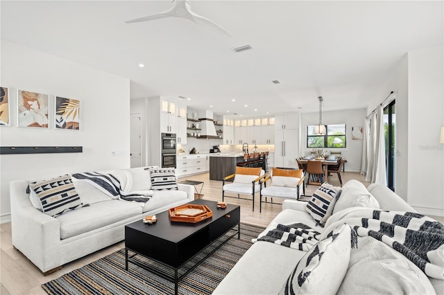 living room with ceiling fan and light wood-type flooring