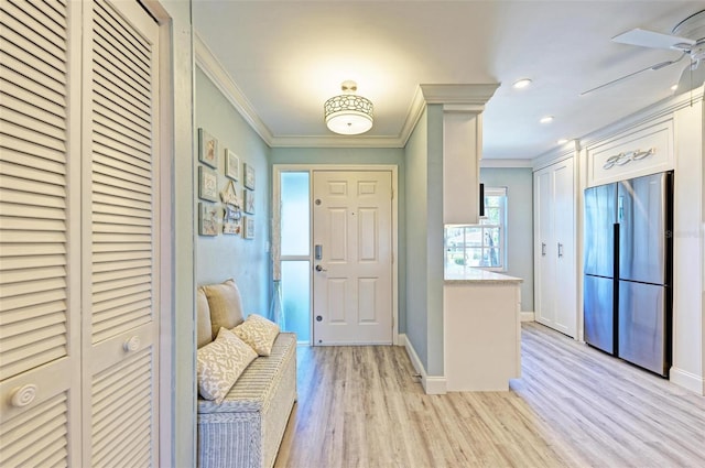 interior space featuring ceiling fan, light wood-type flooring, and crown molding