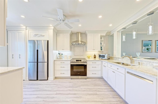 kitchen featuring white cabinets, sink, wall chimney exhaust hood, light wood-type flooring, and appliances with stainless steel finishes