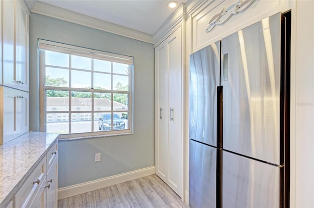 kitchen featuring light stone countertops, white cabinetry, and stainless steel refrigerator