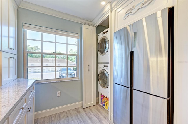 laundry area featuring light hardwood / wood-style flooring, stacked washer / dryer, and ornamental molding