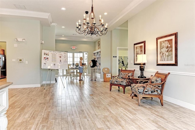 sitting room with a notable chandelier, light wood-type flooring, and crown molding