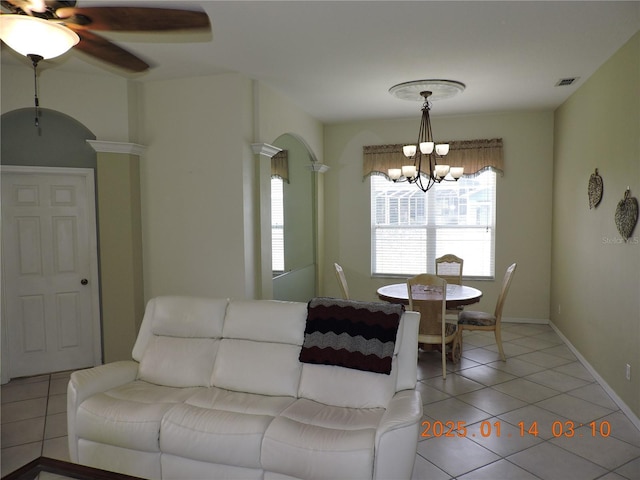 tiled living room with ceiling fan with notable chandelier