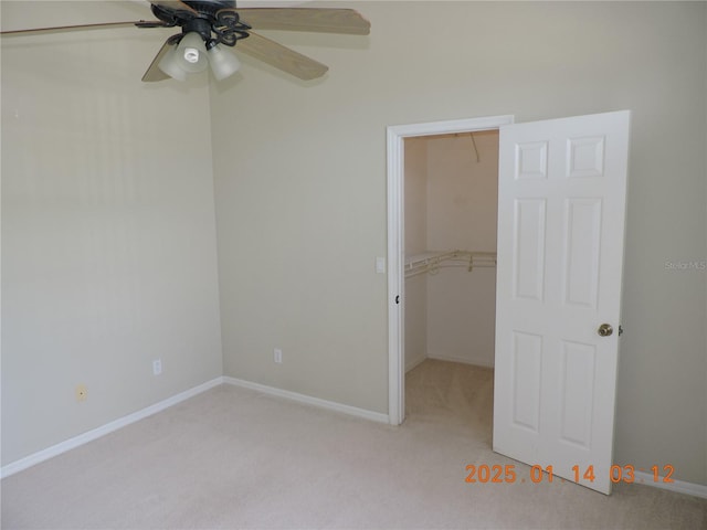 unfurnished bedroom with ceiling fan, a walk in closet, a closet, and light carpet