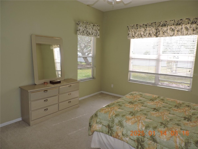 bedroom with light colored carpet, ceiling fan, and multiple windows