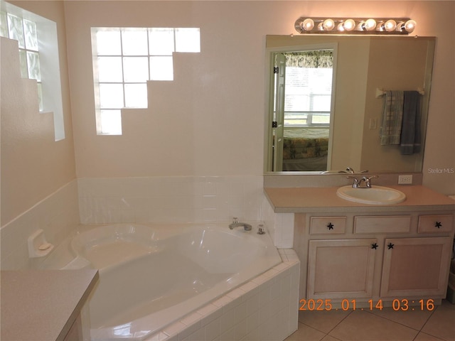 bathroom featuring tile patterned flooring, vanity, and tiled tub