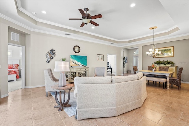 living room featuring ceiling fan with notable chandelier, a tray ceiling, and ornamental molding