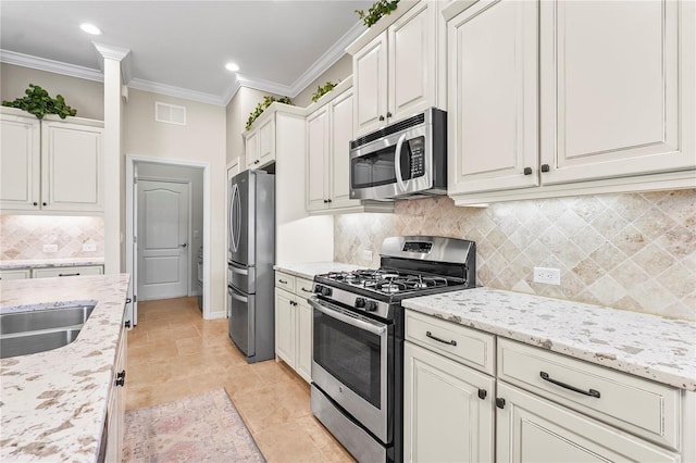 kitchen with light stone countertops, decorative backsplash, ornamental molding, stainless steel appliances, and white cabinets