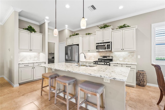 kitchen featuring a center island with sink, hanging light fixtures, sink, light stone countertops, and appliances with stainless steel finishes