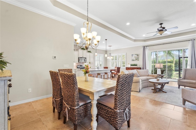 dining room with light tile patterned floors, ceiling fan with notable chandelier, a tray ceiling, and ornamental molding