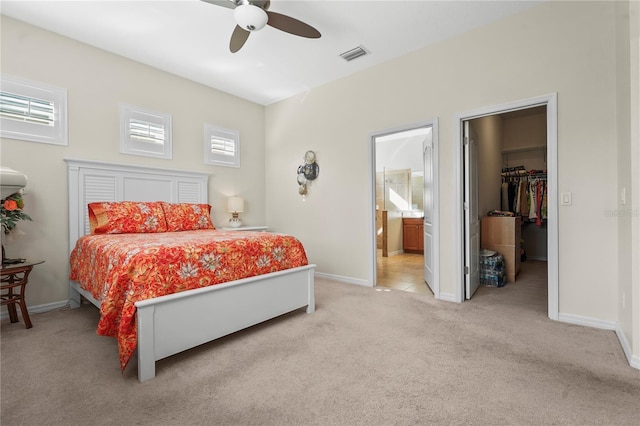 bedroom featuring a walk in closet, ensuite bath, ceiling fan, light colored carpet, and a closet