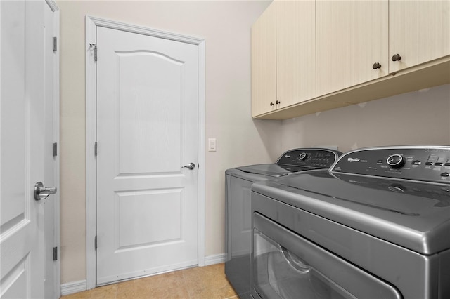 clothes washing area with washer and clothes dryer, light tile patterned flooring, and cabinets