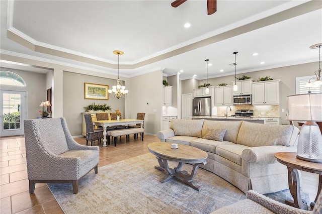 living area with a tray ceiling, crown molding, an inviting chandelier, and light tile patterned floors