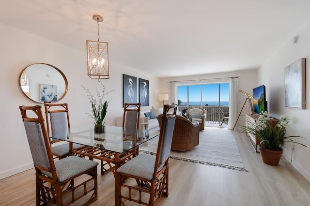 dining space with light hardwood / wood-style flooring and an inviting chandelier