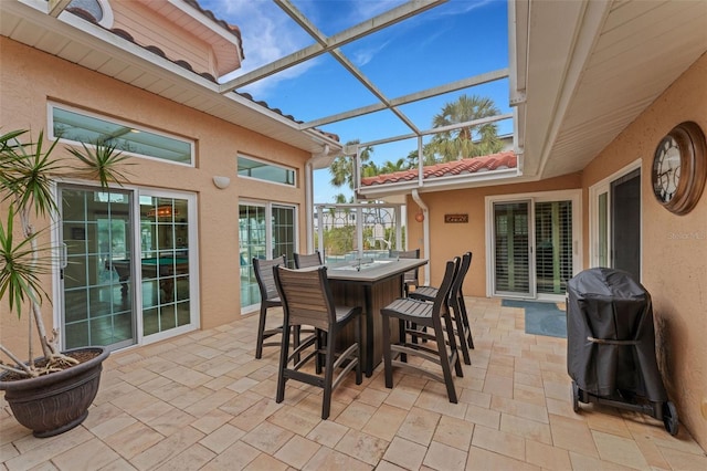 view of patio with a bar, a grill, and a lanai