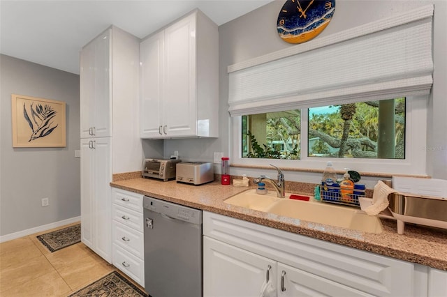 kitchen with sink, dishwasher, white cabinetry, light stone counters, and light tile patterned flooring