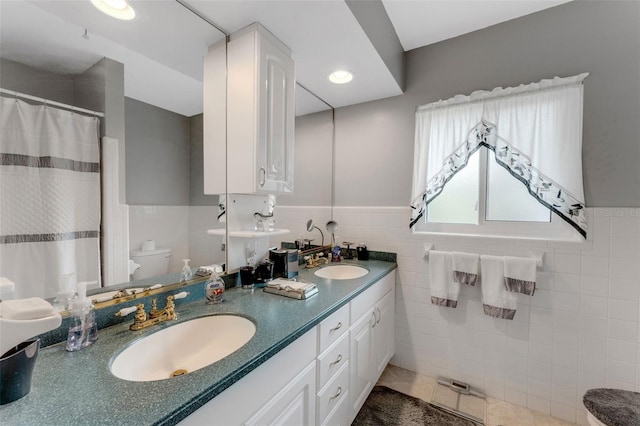 bathroom with vanity, toilet, tile patterned flooring, and tile walls