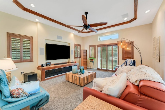 carpeted living room with crown molding, ceiling fan, and a tray ceiling