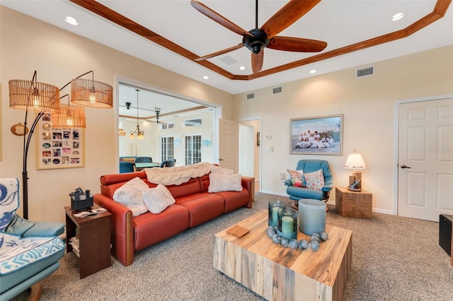 living room featuring a raised ceiling, crown molding, carpet floors, and ceiling fan