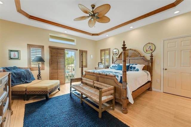 bedroom with ceiling fan, a tray ceiling, light hardwood / wood-style floors, and access to outside