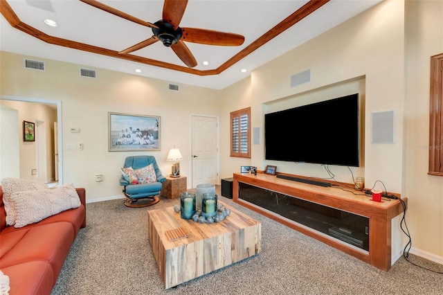 carpeted living room with ceiling fan and a raised ceiling