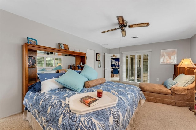 carpeted bedroom with access to exterior, visible vents, and a ceiling fan