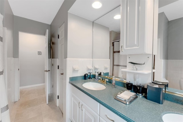 bathroom with double vanity, tile walls, wainscoting, and a sink