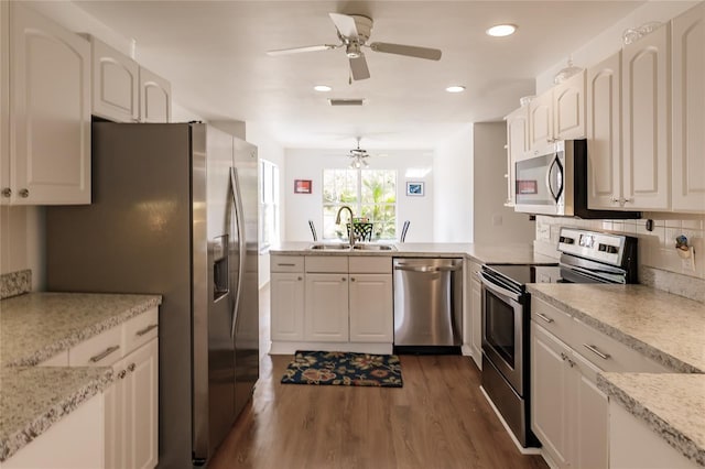 kitchen featuring white cabinetry, stainless steel appliances, dark hardwood / wood-style floors, tasteful backsplash, and sink