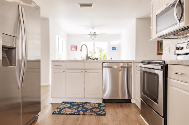 kitchen with ceiling fan, appliances with stainless steel finishes, light hardwood / wood-style floors, and white cabinetry