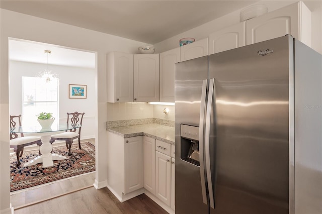 kitchen with white cabinetry, stainless steel refrigerator with ice dispenser, decorative backsplash, decorative light fixtures, and dark wood-type flooring