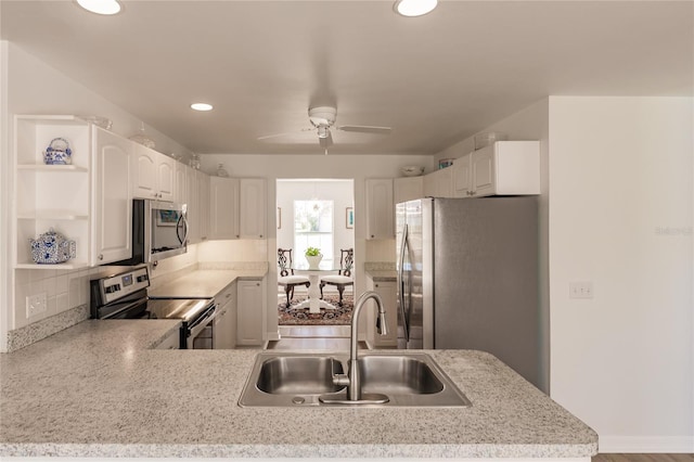 kitchen featuring kitchen peninsula, stainless steel appliances, decorative backsplash, white cabinets, and sink