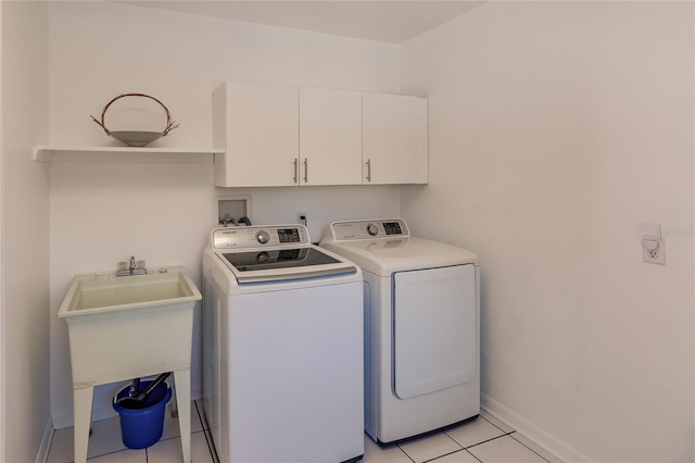 laundry area with washing machine and dryer, cabinets, light tile patterned flooring, and sink