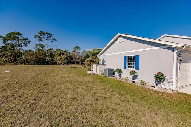 view of side of home with a garage, central AC, and a yard