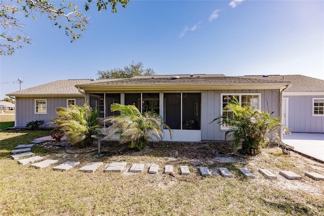 back of house with a sunroom and a lawn