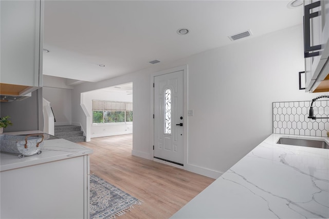 foyer entrance with light hardwood / wood-style flooring and sink