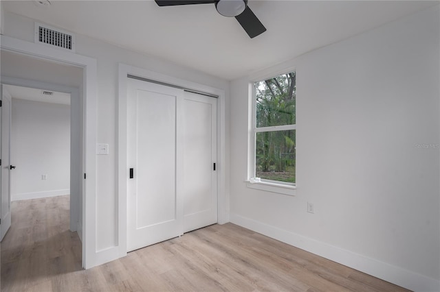 unfurnished bedroom with ceiling fan, light hardwood / wood-style floors, multiple windows, and a closet