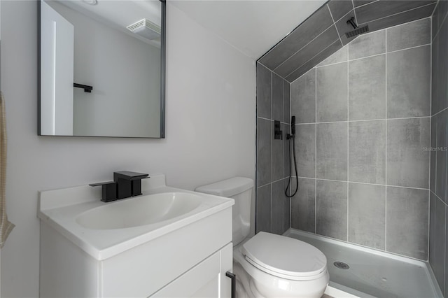 bathroom with tiled shower, vanity, and toilet