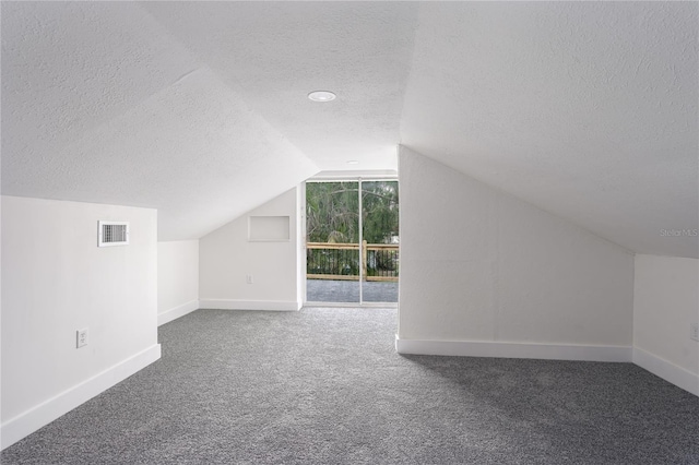 bonus room with vaulted ceiling, carpet floors, and a textured ceiling