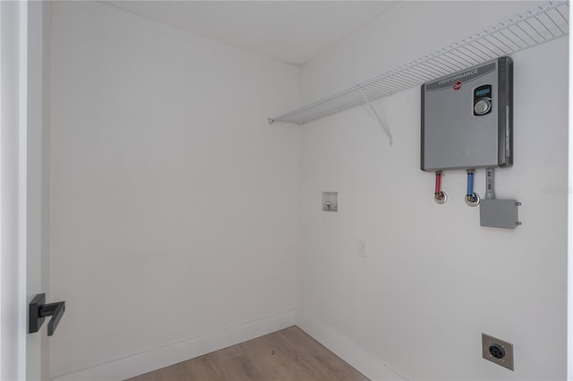 washroom featuring hookup for an electric dryer, water heater, light hardwood / wood-style floors, and washer hookup