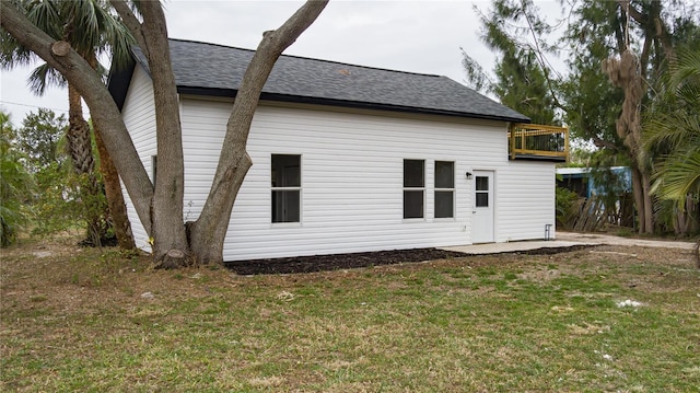 rear view of house with a balcony and a lawn